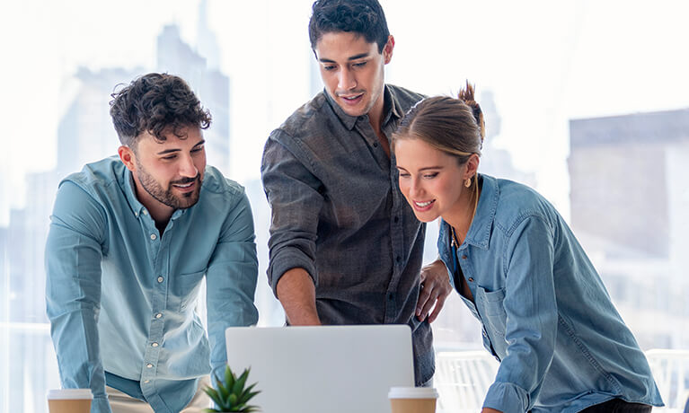 Colleagues collaborating around a laptop in an office