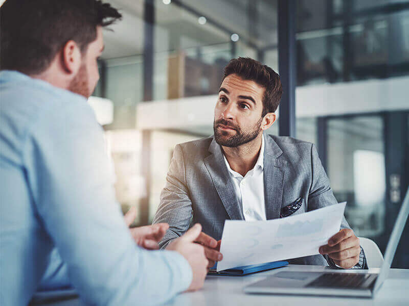 Two men reviewing statistics at desk