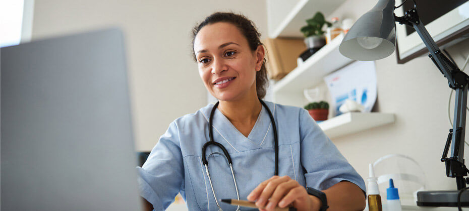 nurse smiling at a desktop computer